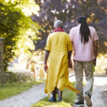 Senior Couple Walking Pet Bulldog In Countryside