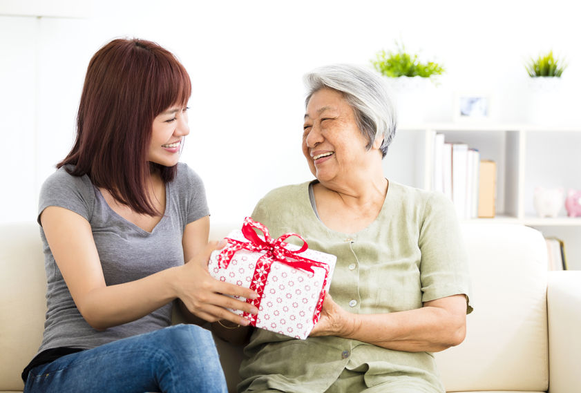 happy young woman giving present to grandmother